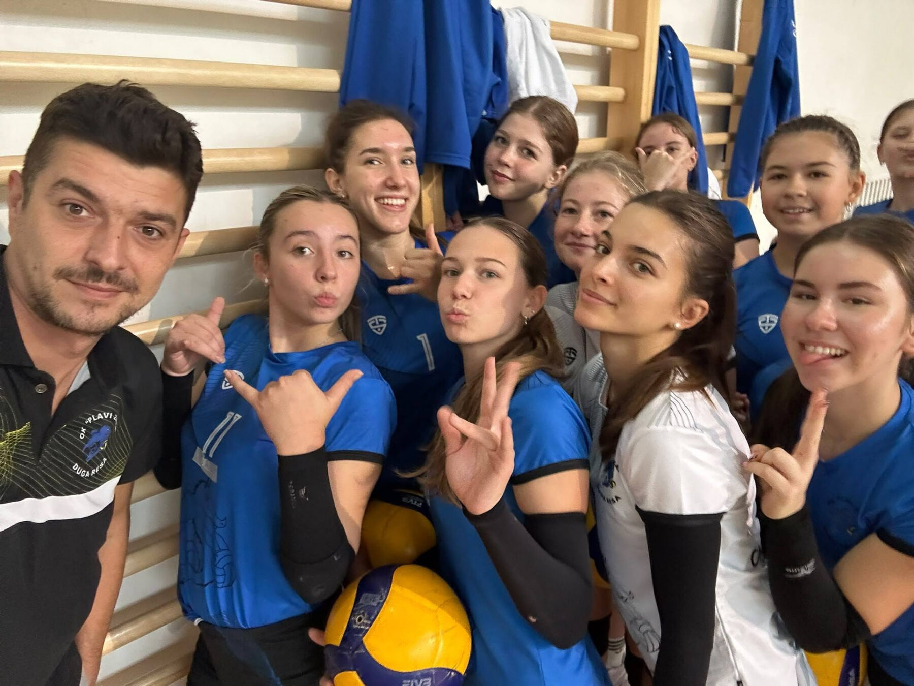 Volleyball players gathered at the net inside a sports hall